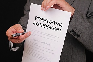 a lawyer holding a prenup agreement and a pen for a high net worth couple