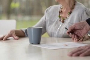 man offering pen to old women to sign divorce agreement