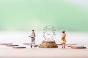 miniature angry woman with miniature man and stack coins over blurred green garden