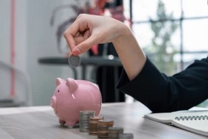 women putting coin in piggy bank
