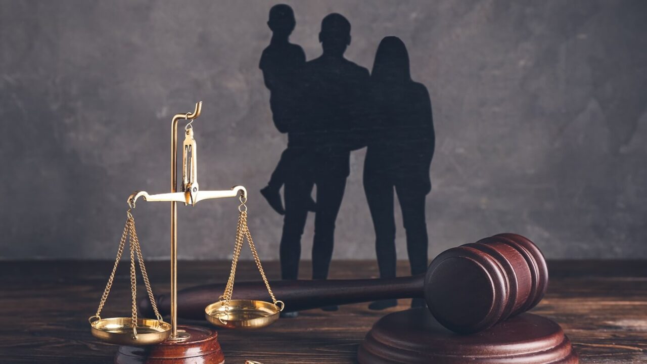 family figures with judge's gavel and justice scales on dark wooden background
