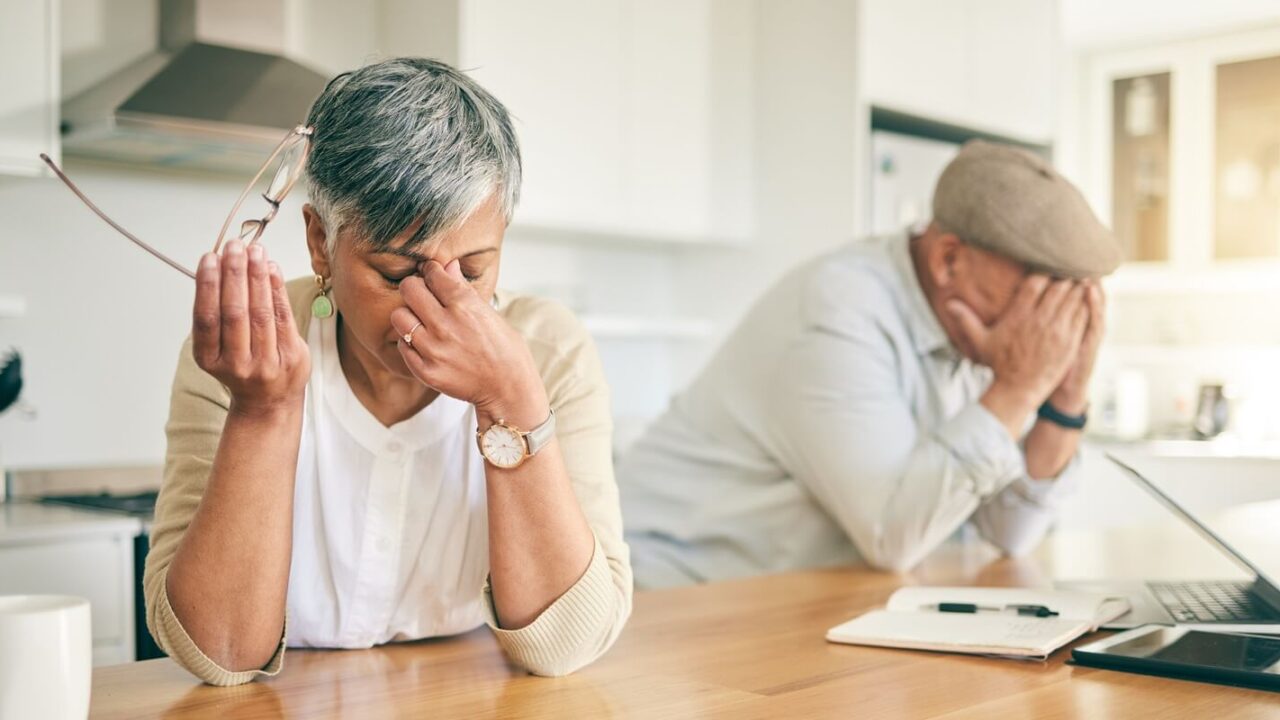 frustrated senior couple, headache and fight in divorce, debt or financial crisis together at home