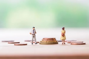 selective focus of miniature angry woman with miniature man and stack coins over blurred green garden background