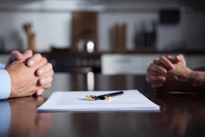 partial view of couple sitting at table with clenched hands near divorce documents discussing men's rights